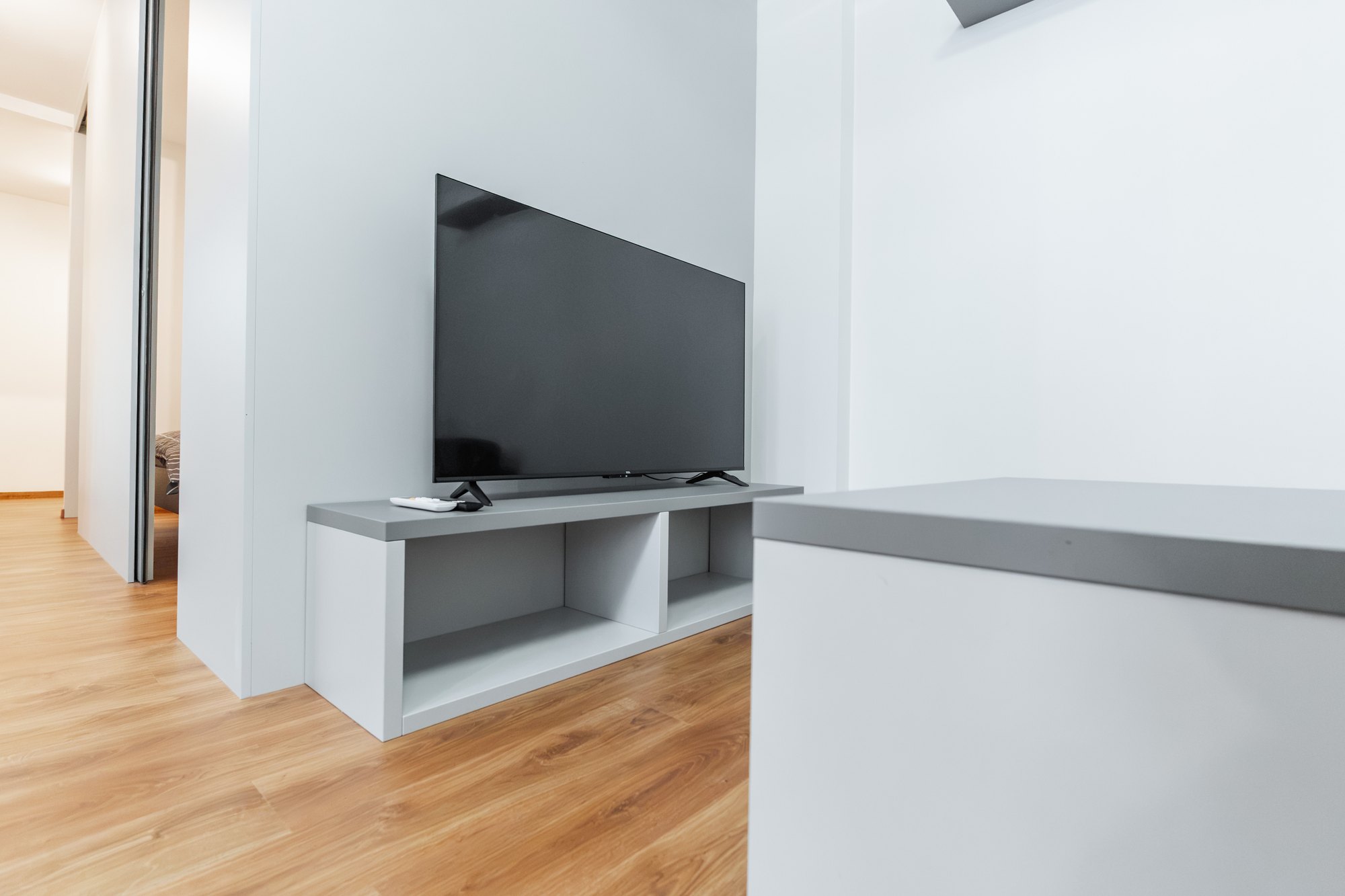 Low, custom-made TV unit in a dusty grey and white combination with open shelves, Bratislava.