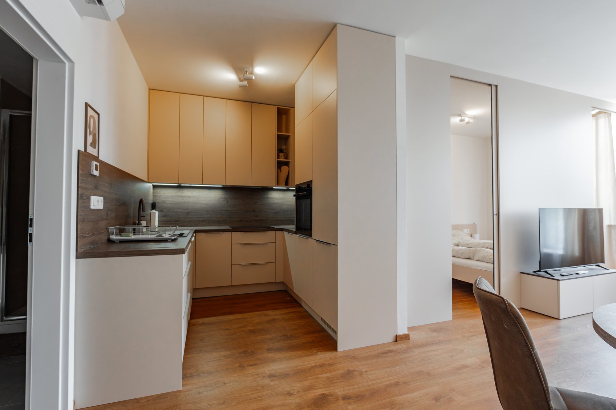 U-shaped kitchen unit with tall floor-to-ceiling cabinets in Satin décor, worktop and backsplash in Brown Davos Oak décor, Bratislava.