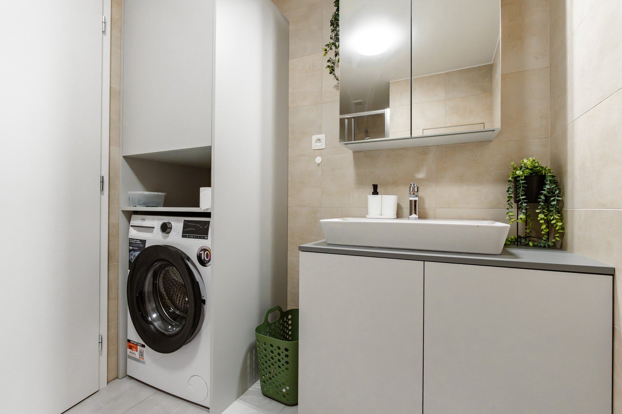 Built-in washing machine cabinet with an open shelf and a bathroom vanity unit in dusty grey laminate, Bratislava.