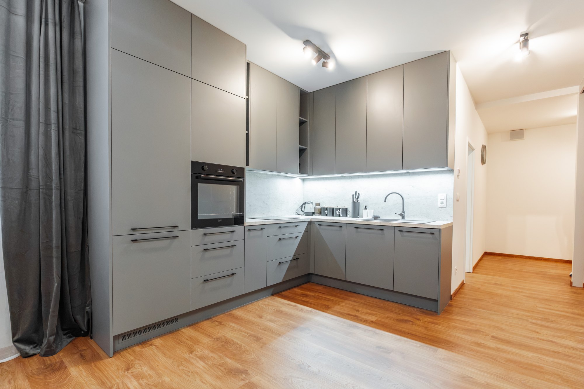 Custom-made corner kitchen in dusty grey laminate decor with a San Luca Marble worktop and tall floor-to-ceiling units, Bratislava.