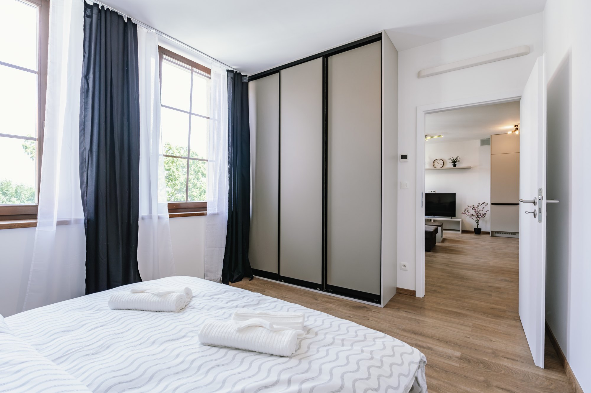 A built-in wardrobe with sliding doors in Cashmere Grey, laminated chipboard, in a bedroom with a wooden floor, Bratislava.