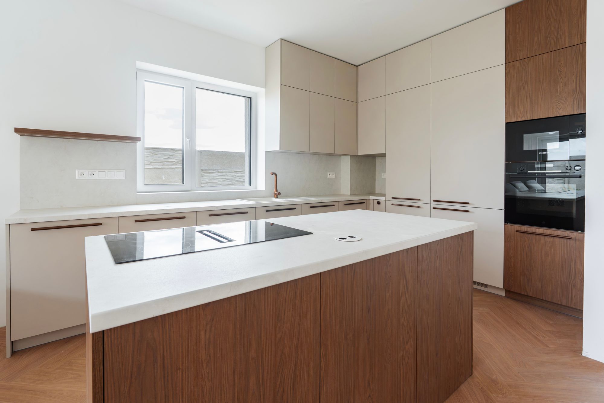 Kitchen unit with an island combining cashmere and Brown Casella Oak, white composite stone worktop, tall floor-to-ceiling cabinets, Rovinka.
