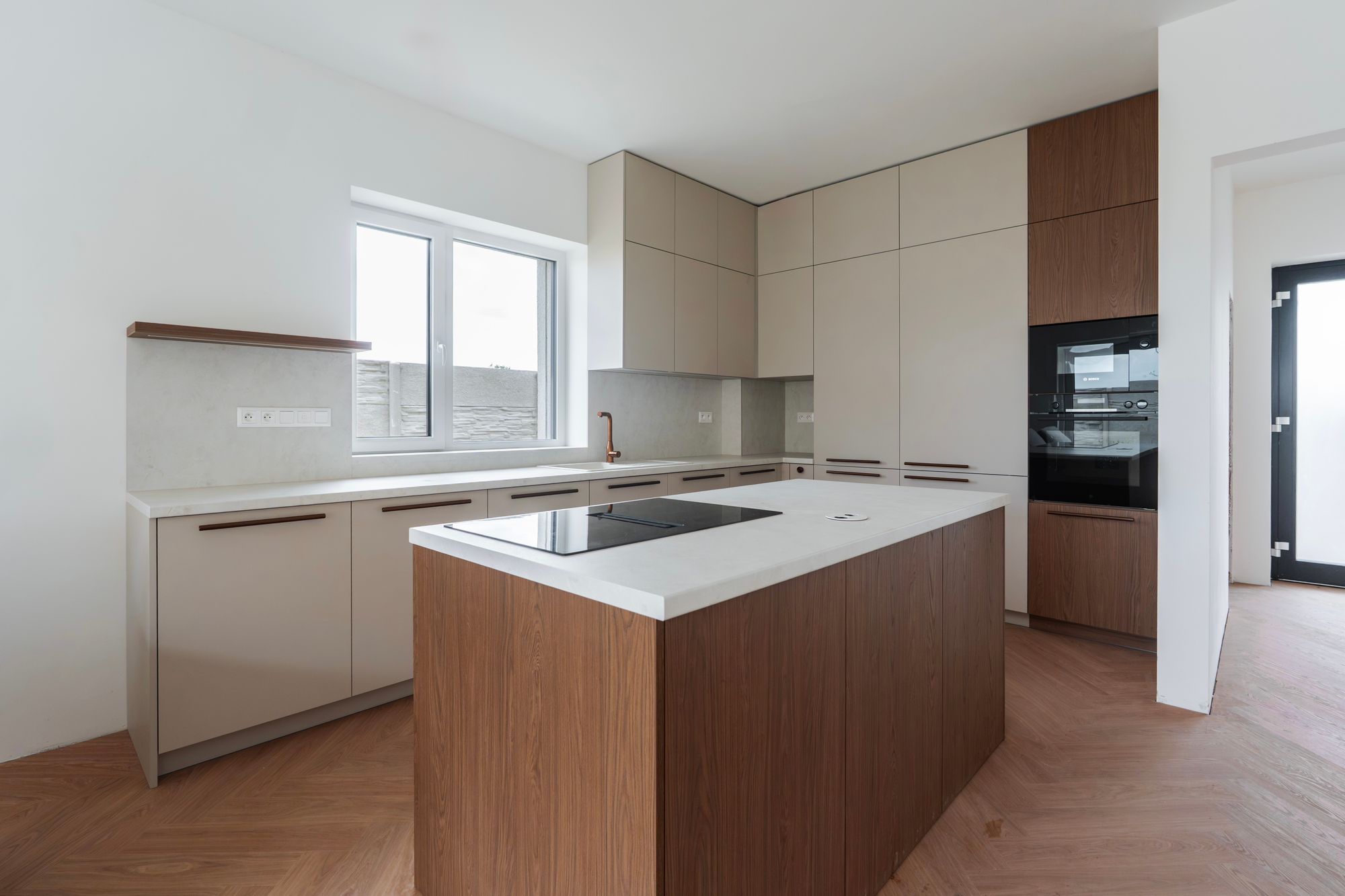 Kitchen unit with an island in cashmere and Brown Casella Oak décor, tall floor-to-ceiling cabinets and built-in appliances, Rovinka.