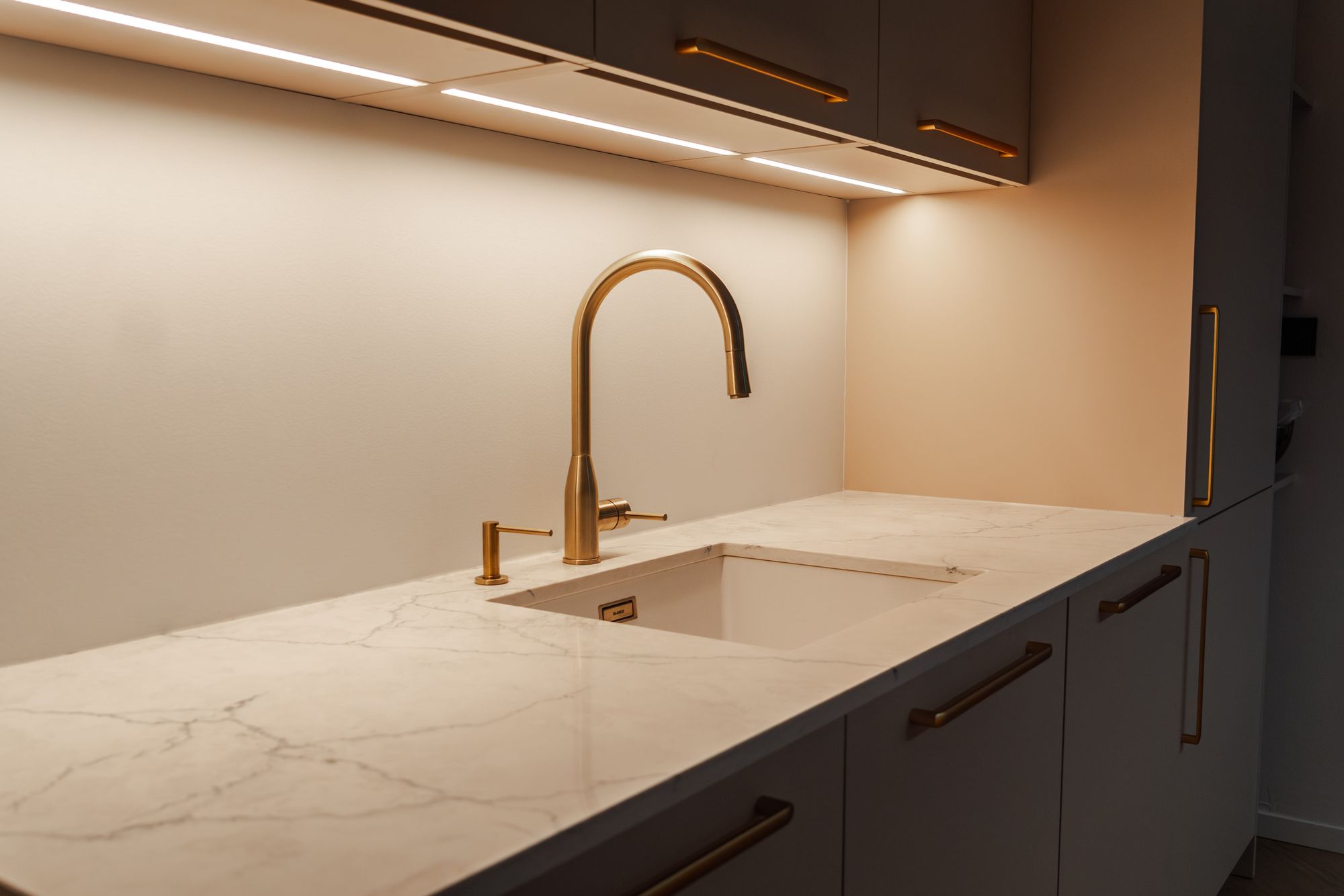 Detail pracovnej dosky z kremeňa AVANT Quartz Calacatta Concorde s vaničkou a zlatou batériou, podšafíkové LED osvetlenie, Stupava.