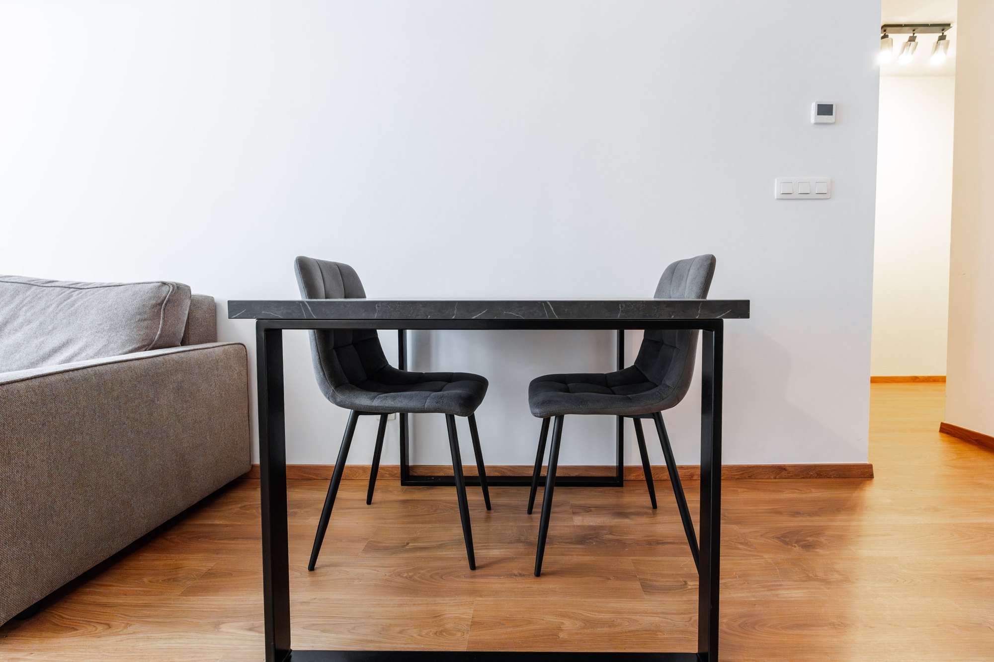 Dining table with a black Pietra Grigia-effect top and metal frame, grey upholstered chairs, Bratislava.