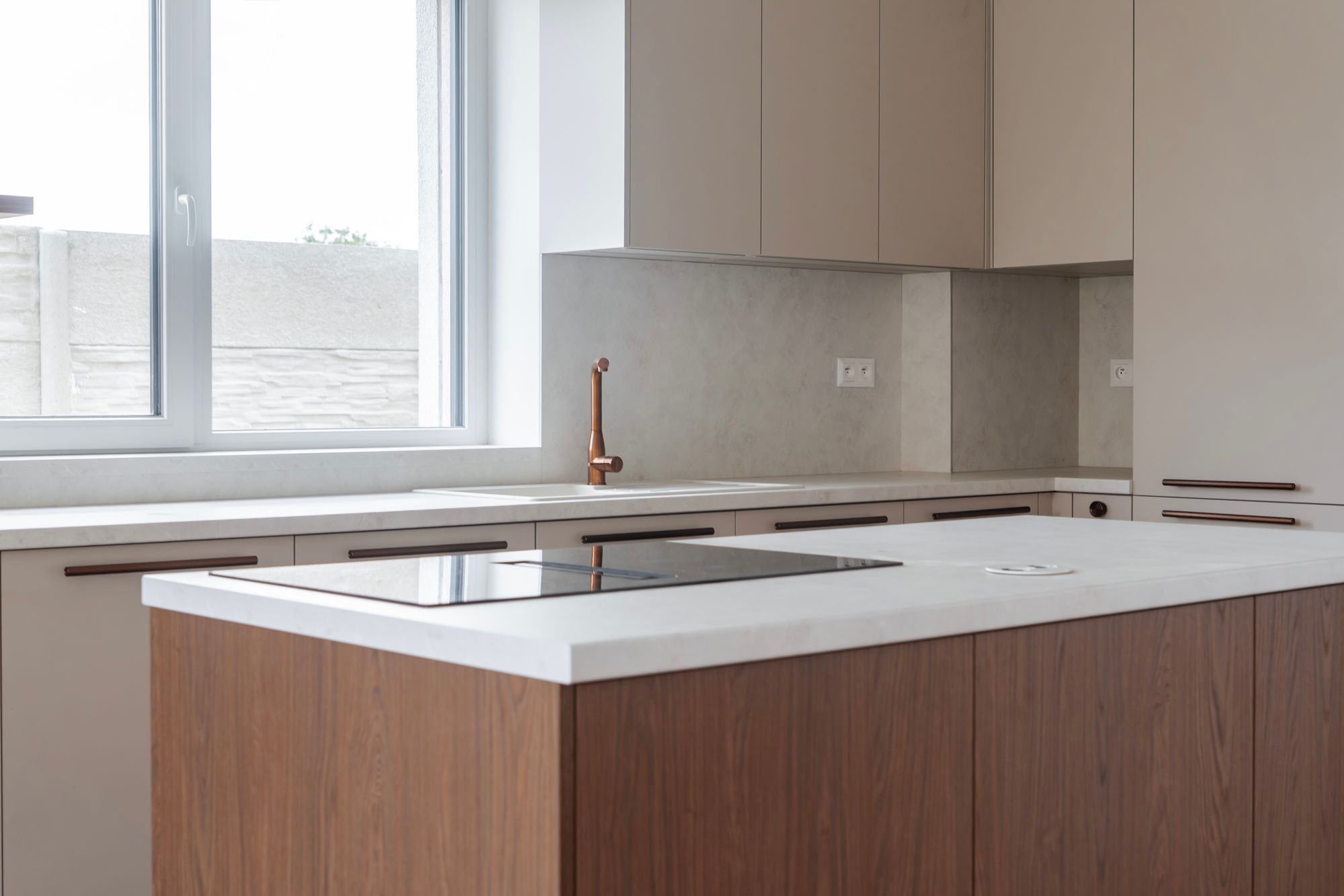 Kitchen unit with an island combining cashmere and Brown Casella Oak, white composite stone worktop and copper details, Rovinka.