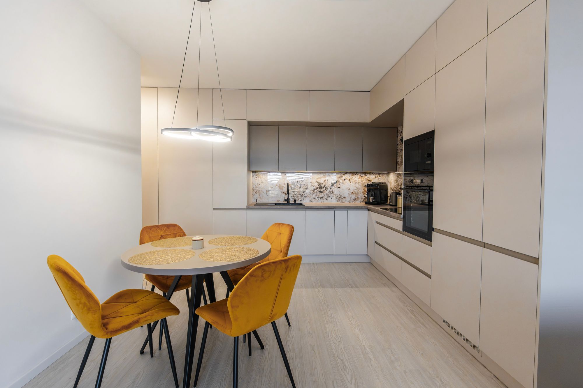 A kitchen in Cashmere Grey combined with Stone Grey decor and a Titanit Sandy Beige worktop. Laminated chipboard is complemented by black appliances and a striking splashback, creating an elegant contrast.