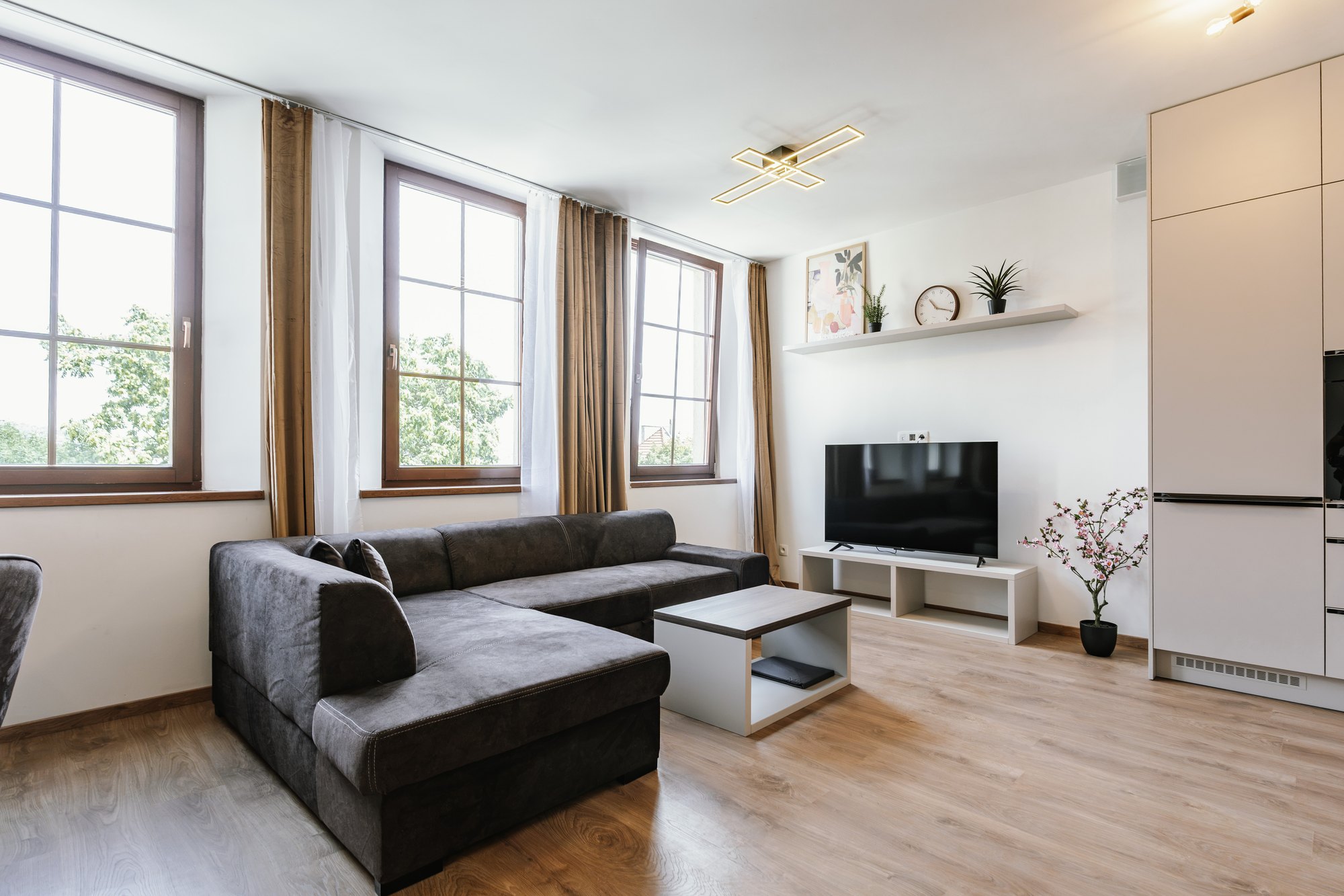 A tall built-in wardrobe in Cashmere Grey with a laminated chipboard surface complements the living room with a sofa, Bratislava.