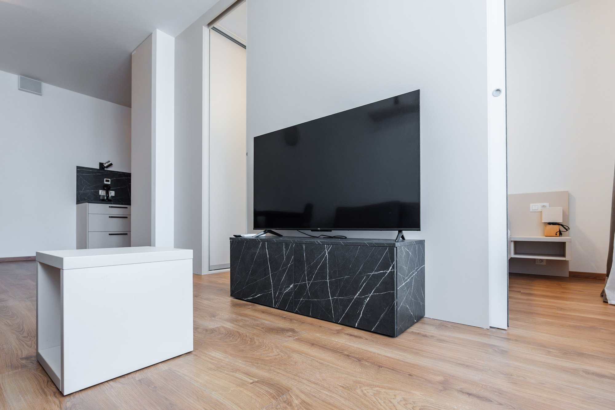 TV unit in black Pietra Grigia marble-effect finish with a white chest of drawers in the bedroom, laminated chipboard, Bratislava.