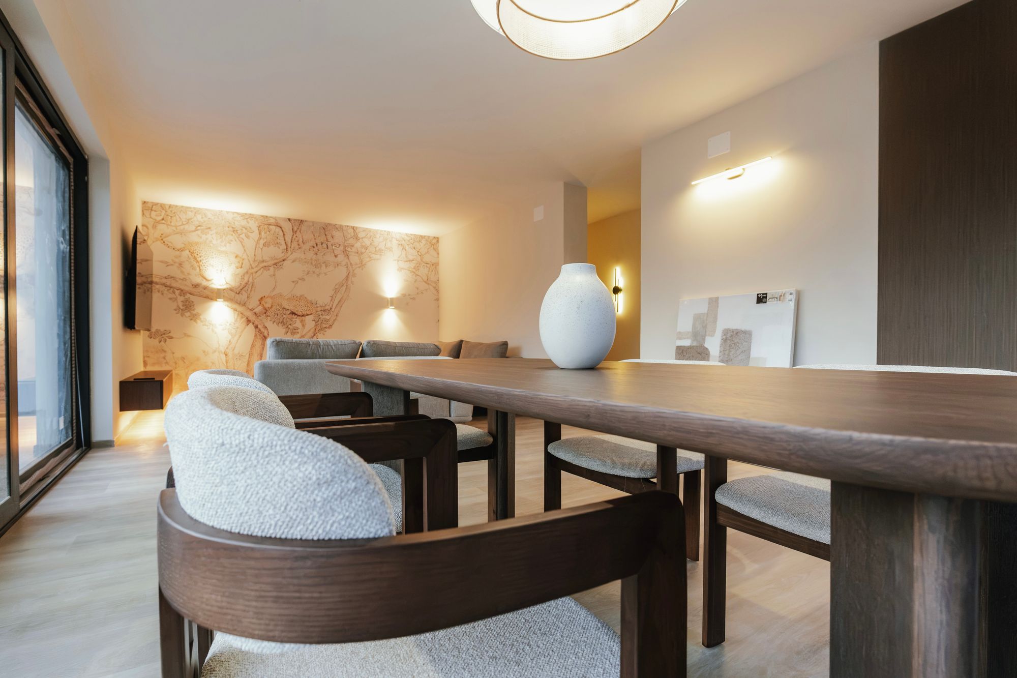 Dining table with upholstered chairs in solid Brown Tonsberg Oak, with a living room feature wall in the background, Croatia – Krk.